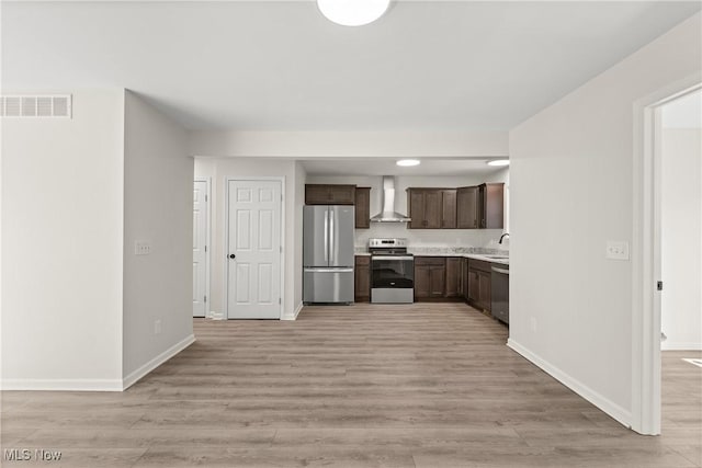 kitchen featuring visible vents, wall chimney range hood, stainless steel appliances, dark brown cabinetry, and light countertops