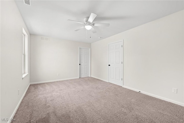 empty room with visible vents, baseboards, ceiling fan, and carpet flooring