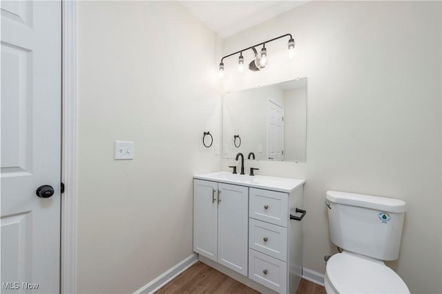 bathroom featuring vanity, toilet, wood finished floors, and baseboards