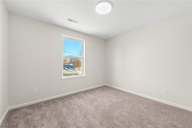 carpeted spare room featuring visible vents and baseboards