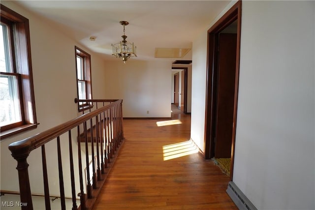 3390 Meese Rd NE, Louisville, OH 44641 - hallway with baseboards, an upstairs landing, wood finished floors, a notable chandelier, and a baseboard radiator
