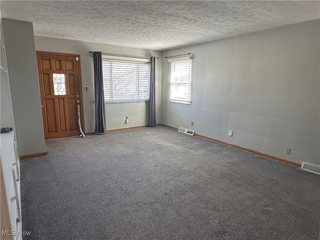 empty room featuring visible vents, carpet, and a textured ceiling