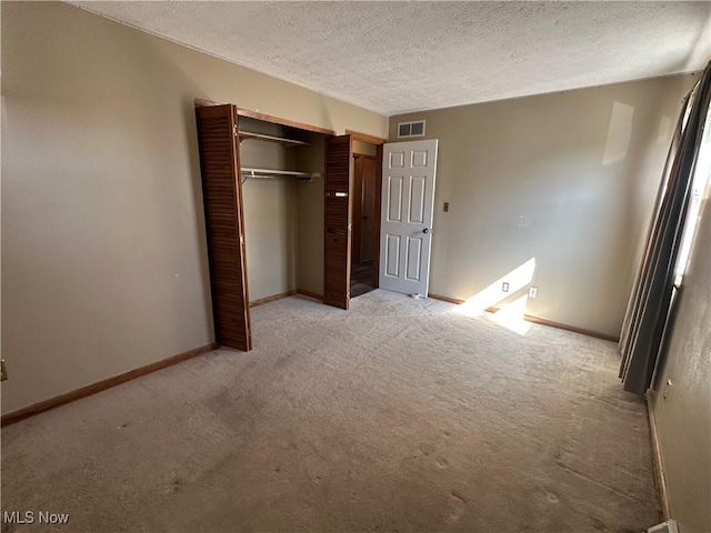 unfurnished bedroom featuring visible vents, baseboards, a closet, a textured ceiling, and light colored carpet