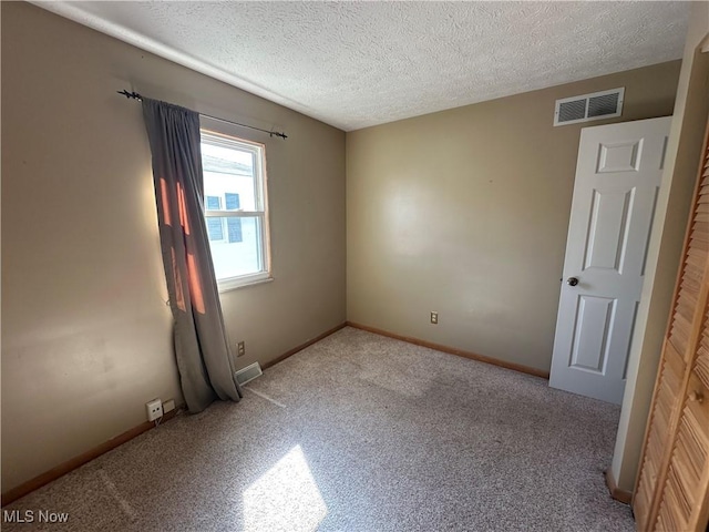 unfurnished room with baseboards, visible vents, and a textured ceiling