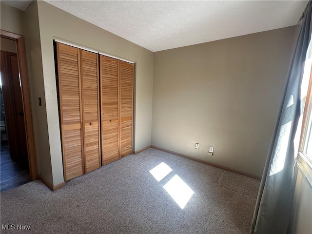 unfurnished bedroom with baseboards, carpet, a closet, and a textured ceiling