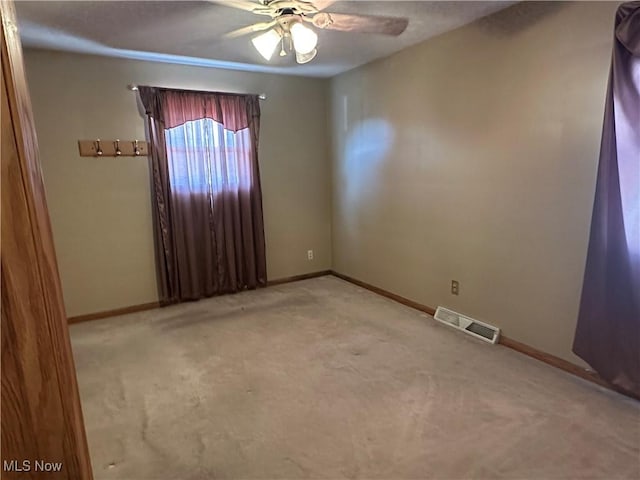 carpeted empty room featuring visible vents, ceiling fan, and baseboards