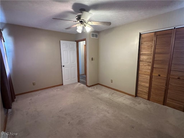 unfurnished bedroom with baseboards, visible vents, a closet, a textured ceiling, and light colored carpet