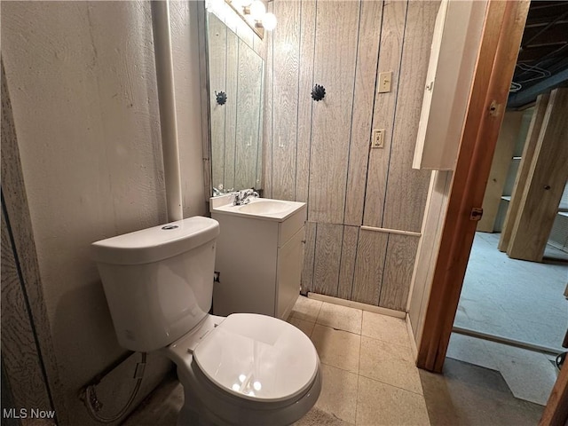 bathroom featuring wooden walls, toilet, and vanity