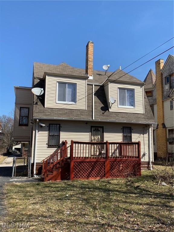 rear view of property featuring a wooden deck, a gate, a yard, and a chimney