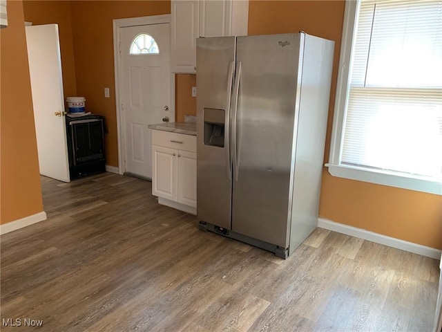 kitchen with wood finished floors, range, stainless steel fridge, and white cabinets