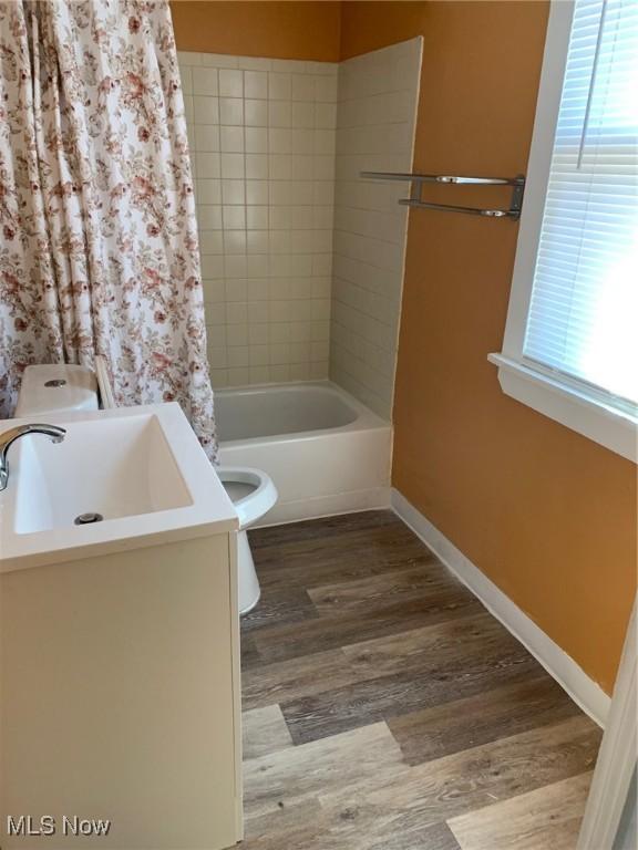 full bathroom featuring baseboards, toilet, shower / tub combo, wood finished floors, and vanity