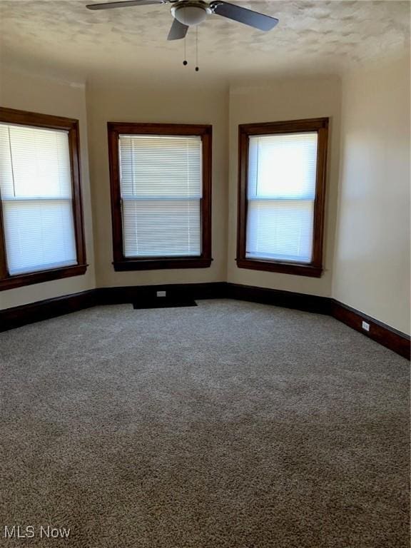 carpeted spare room with baseboards and a ceiling fan