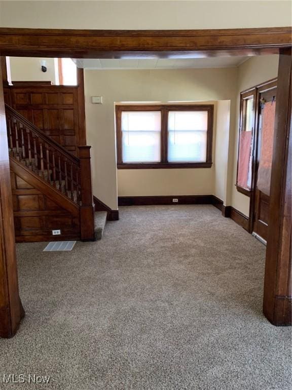 unfurnished living room with stairs, baseboards, and carpet floors