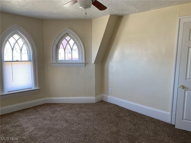 carpeted spare room featuring a healthy amount of sunlight, a textured ceiling, and a ceiling fan