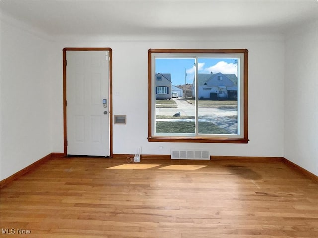 empty room featuring baseboards, visible vents, and light wood finished floors