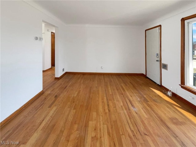 spare room with baseboards and light wood finished floors