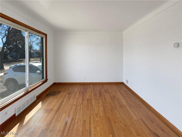 unfurnished room with visible vents, light wood-style flooring, and baseboards