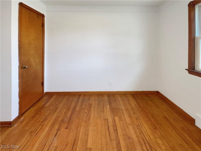 empty room with baseboards, light wood-style floors, and ornamental molding