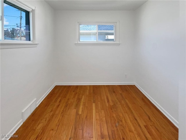 spare room with visible vents, baseboards, and wood finished floors