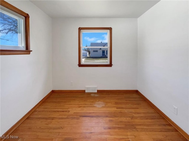 spare room featuring visible vents, light wood-type flooring, and baseboards