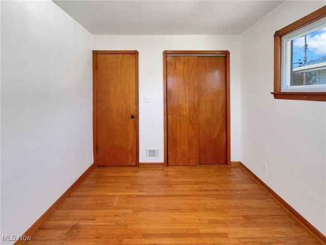 unfurnished bedroom with visible vents, baseboards, a closet, and light wood-style flooring