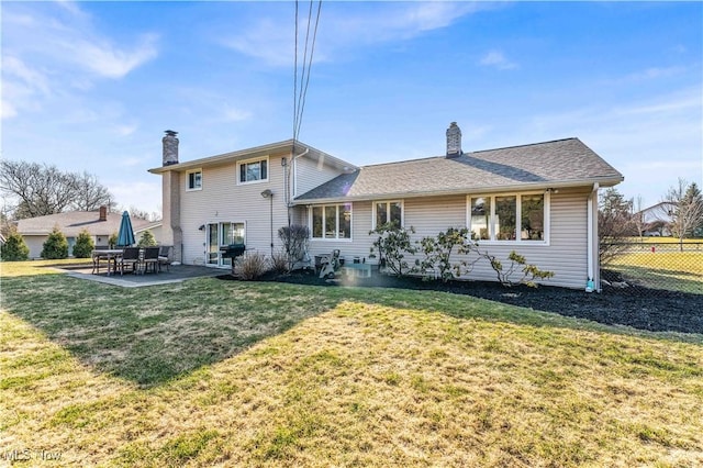 back of property with a yard, a chimney, and a patio