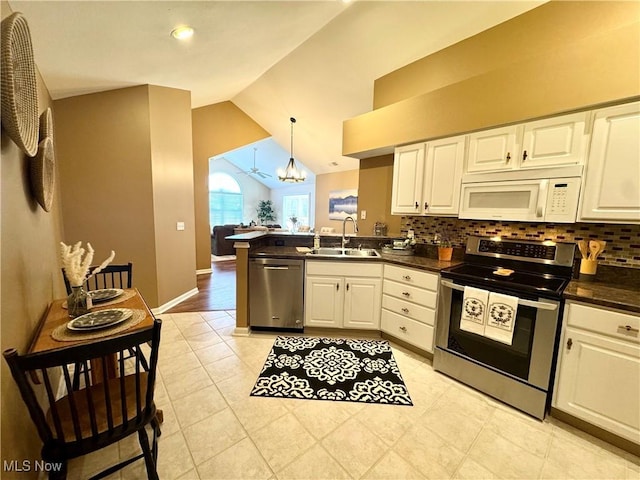 kitchen with a sink, dark countertops, white cabinetry, appliances with stainless steel finishes, and a peninsula