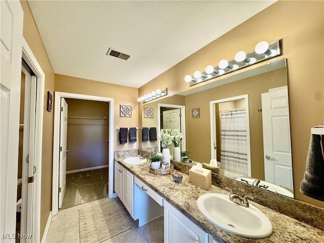 full bath featuring a textured ceiling, visible vents, and a sink