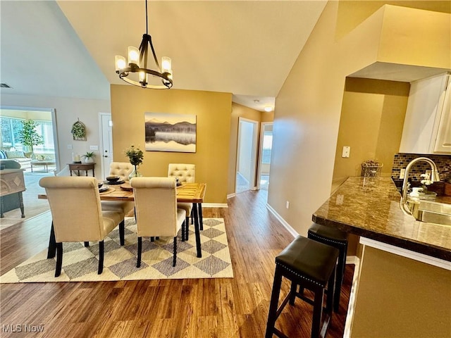 dining area with wood finished floors, baseboards, visible vents, high vaulted ceiling, and an inviting chandelier