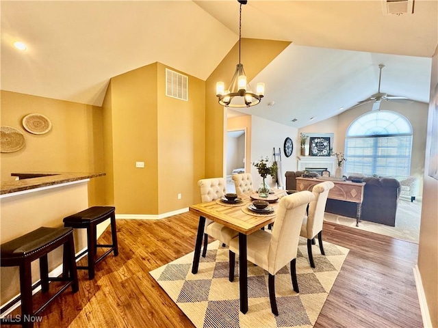 dining space featuring vaulted ceiling, light wood-style floors, visible vents, and baseboards