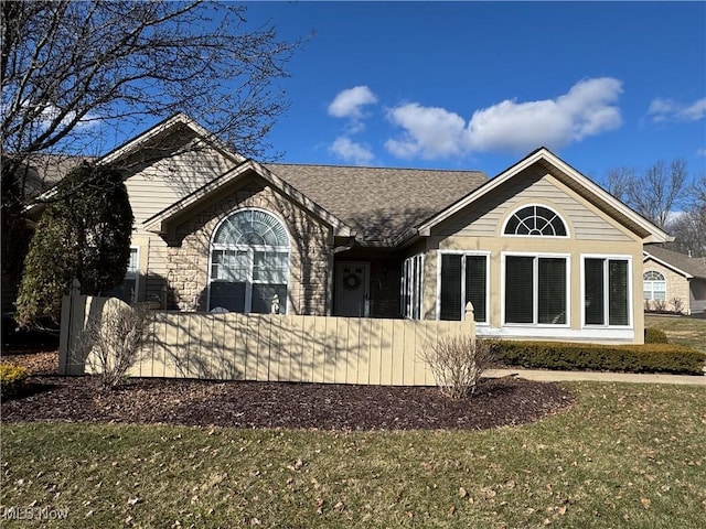 rear view of house featuring fence, a lawn, and a shingled roof