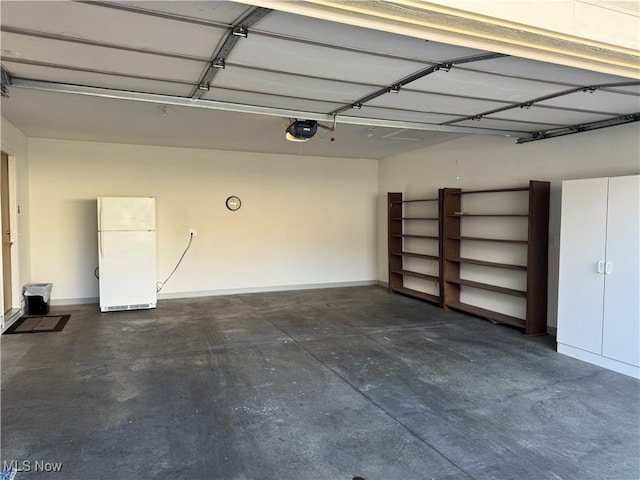 garage featuring a garage door opener, freestanding refrigerator, and baseboards