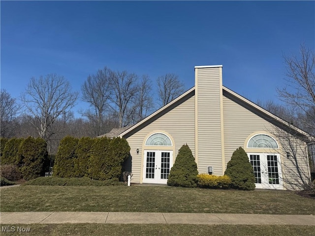 view of home's exterior with a yard, french doors, and a chimney