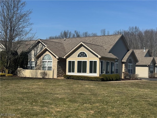 view of front of property with a front lawn, stone siding, and a shingled roof