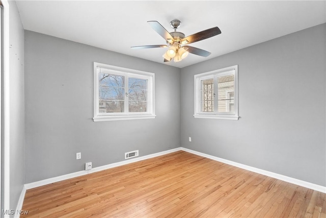 spare room with ceiling fan, baseboards, visible vents, and light wood-type flooring