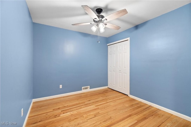 unfurnished bedroom featuring a closet, visible vents, baseboards, and wood finished floors