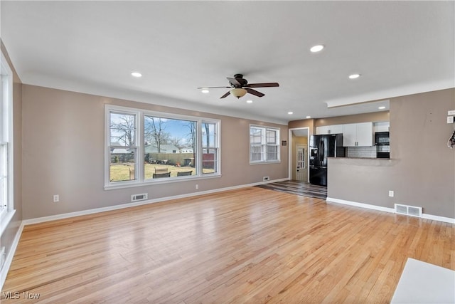 unfurnished living room with light wood finished floors, visible vents, baseboards, and a ceiling fan