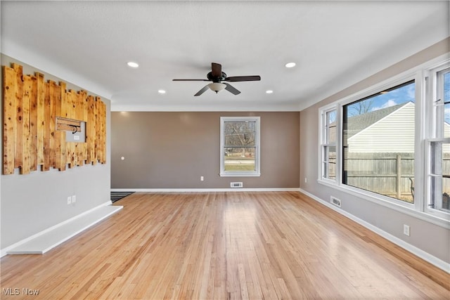 empty room featuring light wood-type flooring, visible vents, baseboards, and a ceiling fan