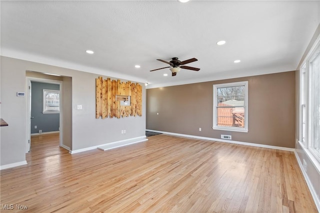 empty room featuring a ceiling fan, plenty of natural light, light wood-style floors, and visible vents