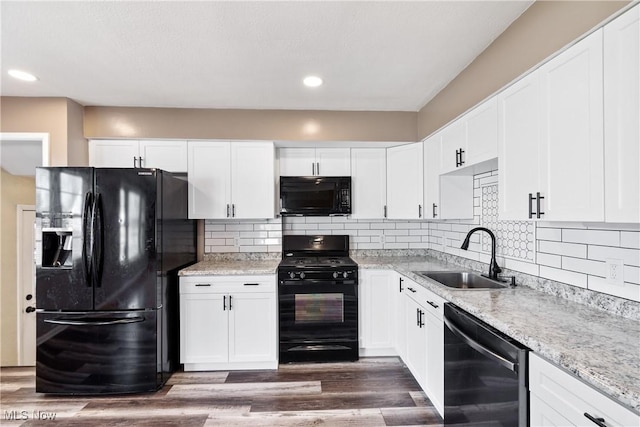 kitchen featuring dark wood finished floors, black appliances, white cabinets, and a sink