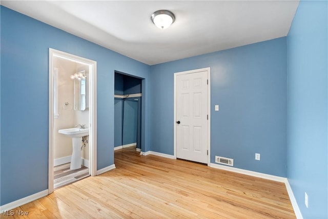 unfurnished bedroom with wood finished floors, visible vents, and baseboards