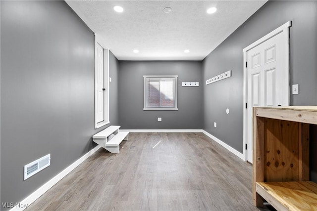 interior space featuring visible vents, baseboards, recessed lighting, wood finished floors, and a textured ceiling