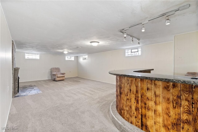 bar featuring rail lighting, a wealth of natural light, bar area, and carpet floors