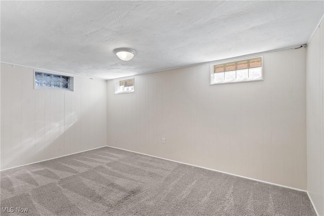 below grade area with a wealth of natural light, a textured ceiling, and carpet floors