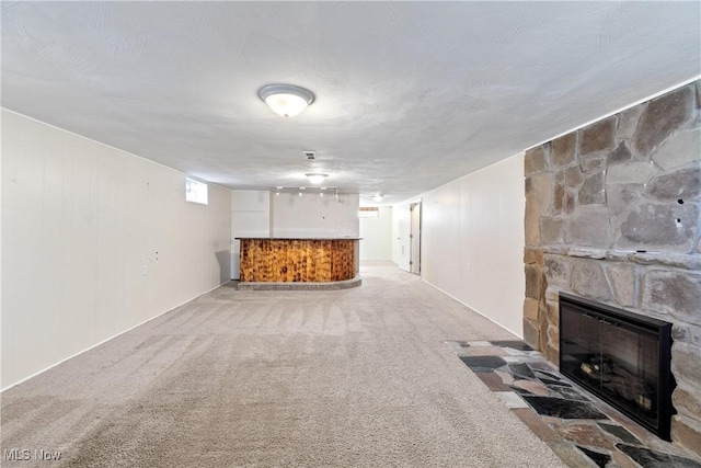 unfurnished living room featuring carpet, a dry bar, and a fireplace