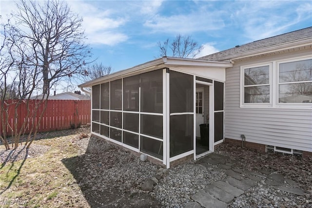 view of outdoor structure featuring a sunroom and fence