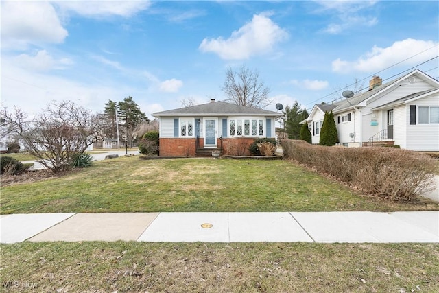 bungalow with entry steps, a front yard, and brick siding