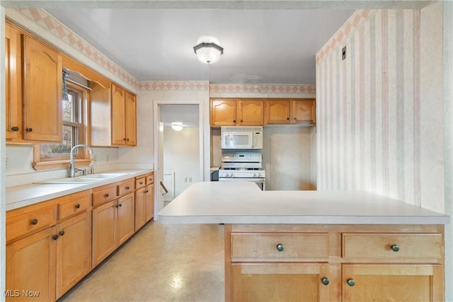 kitchen featuring wallpapered walls, white appliances, light countertops, and a sink