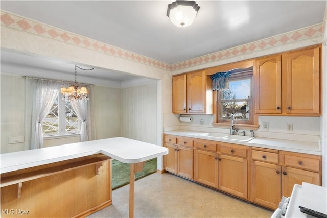 kitchen with wallpapered walls, light countertops, a chandelier, and a sink