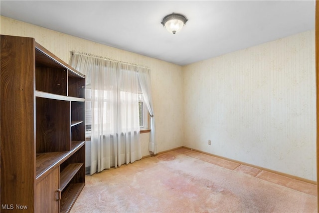 spare room featuring baseboards and light carpet